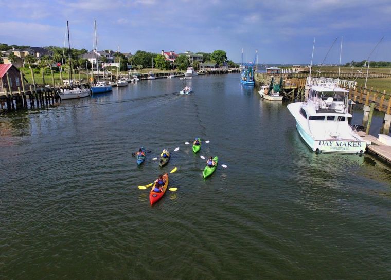 Kayakers paddling a tidal creek through the salt marsh