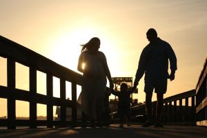 Family silhouetted on a dock at sunset