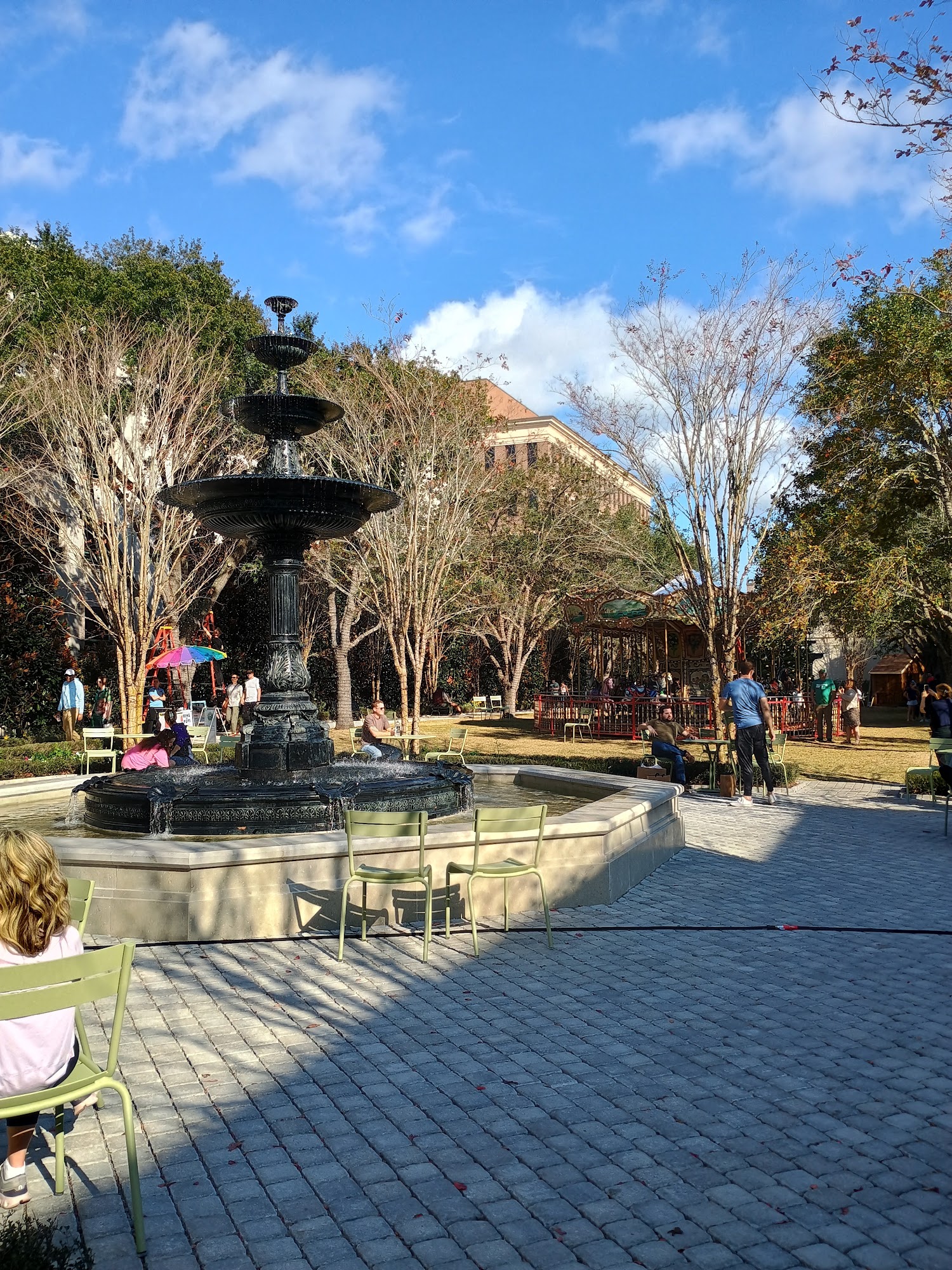 The fountain and lawn at American Gardens on King Street in Charleston, people walking the paths under young trees on a clear day.