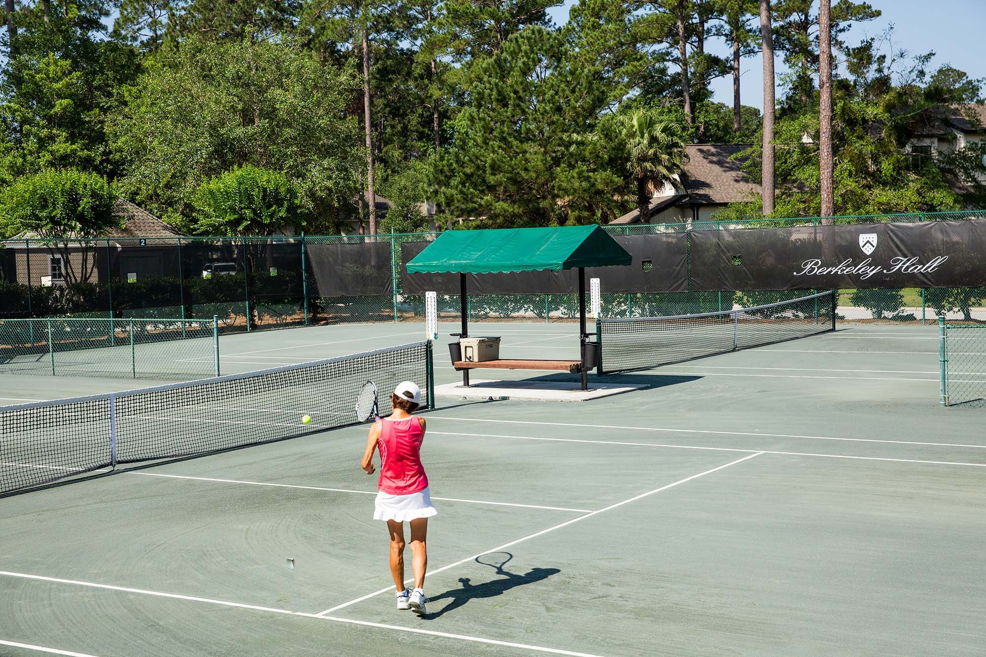 a rally on the club courts, green canopy and windscreen behind