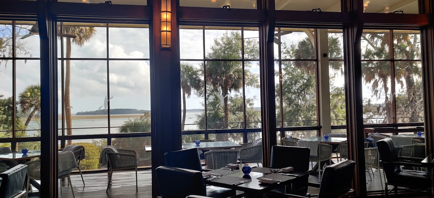 The Canoe Club dining room, tall windows looking out through palmettos to the water.