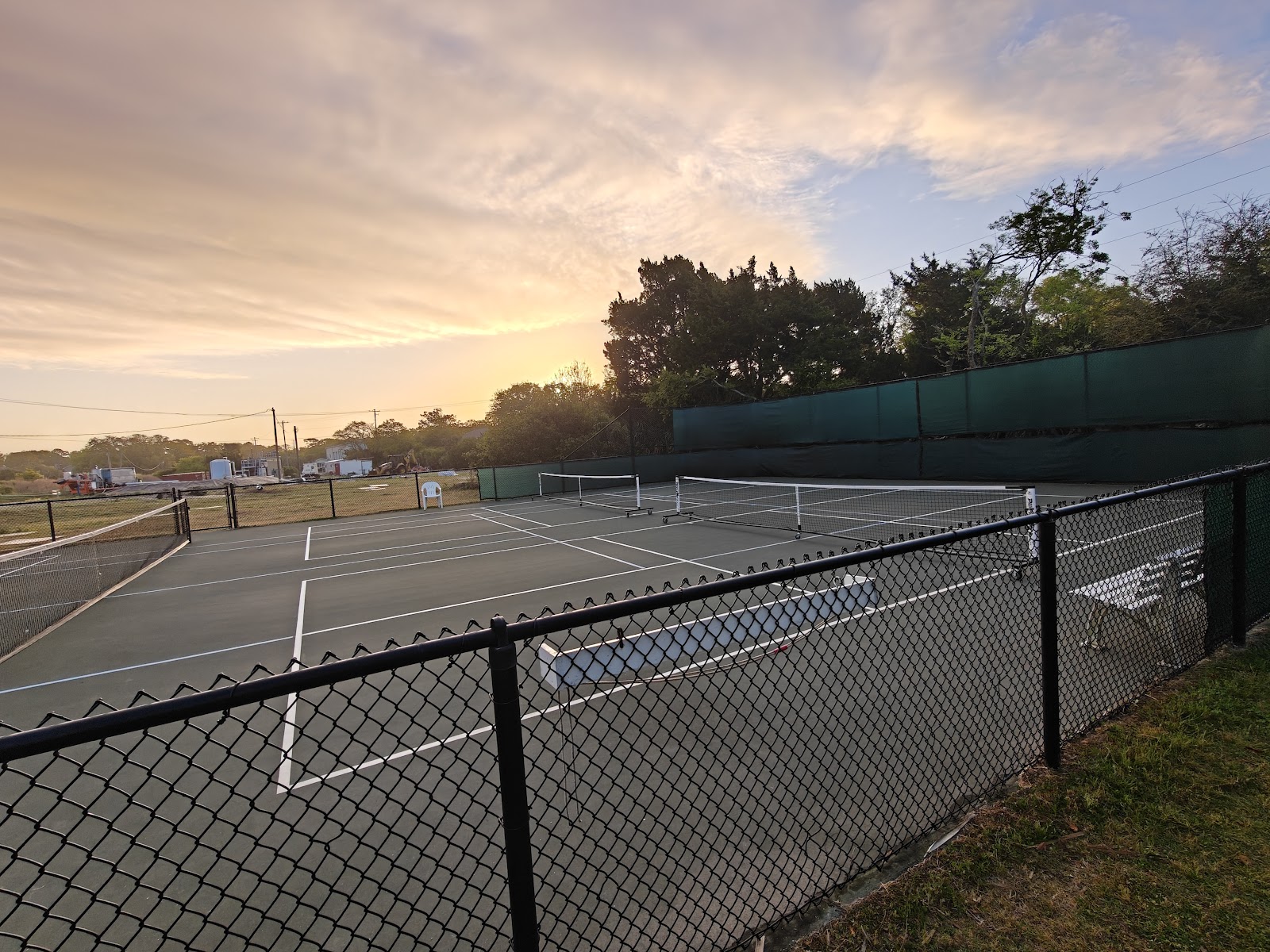 the public courts at first light, nets up behind the fence line