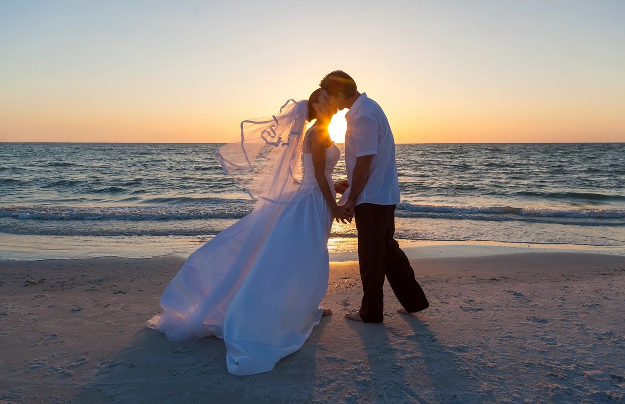 A couple silhouetted against the water at sunset