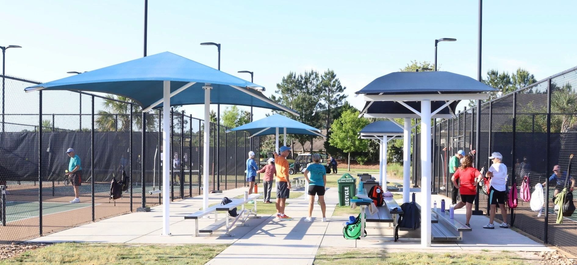players between games under the shade canopies at the courts